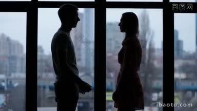 一对<strong>相爱</strong>的情侣的剪影牵手的窗口在城市景观背景慢动作